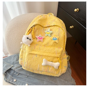 Detail of yellow school backpack with 3D embossed fabric and cute plush star charms