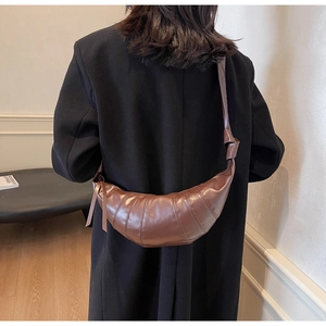 Detail of a dark brown crescent bag with quilted pattern and decorative knotted strap