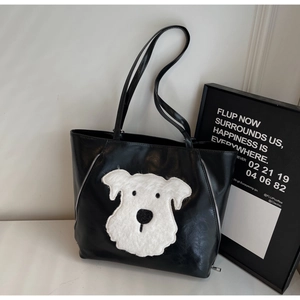 Detail of black tote bag featuring a plush cartoon dog patch and side zipper accents