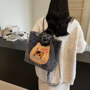 Dark grey corduroy tote bag with cat embroidery shown in a cozy coffee shop setting