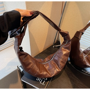 Macro view of dark brown crescent bag with quilted faux leather texture and knotted strap