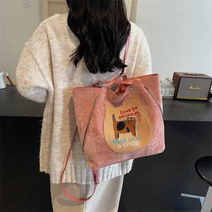 Pink corduroy tote bag with cat embroidery and shoulder strap shown in lifestyle cafe setting