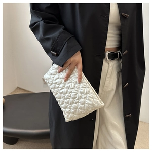 Detailed view of white quilted envelope clutch bag with diamond stitching pattern