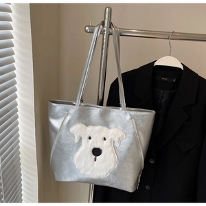Detail of silver metallic tote bag featuring a cute plush dog embroidery and sleek finish