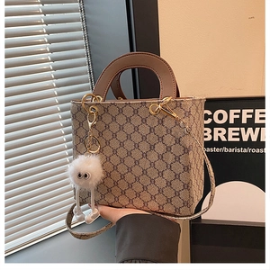 Detail of crossbody tote bag with retro monogram pattern and cute plush charm pendant