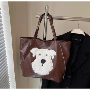 Detail of tan vintage tote bag featuring a cute white plush puppy applique and side zippers