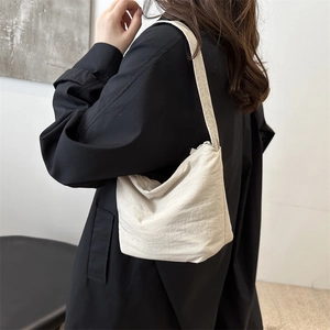Minimalist off-white wrinkled hobo bag shown on model with shoulder strap and zipper