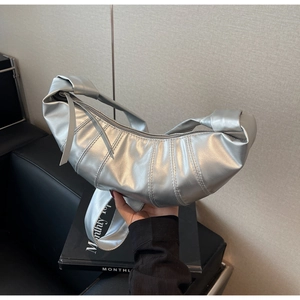 Detail of silver croissant bag featuring metallic texture and signature pleated stitching