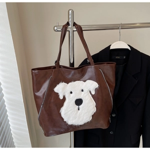 Detail of brown tote bag with white plush dog patch and side silver zipper accents