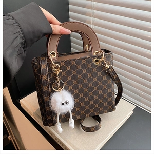 Close-up of vintage monogram shoulder bag with leather handle and plush eye charm