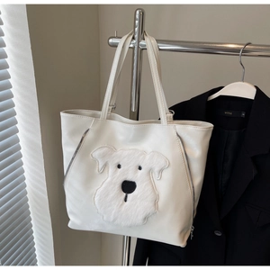 Detail of white PU leather tote bag with a cute plush puppy patch on metal hanger