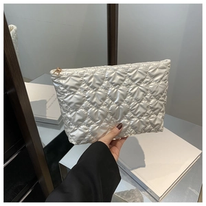 Detail of white heart-quilted handbag with pearl luster finish and gold zipper closure
