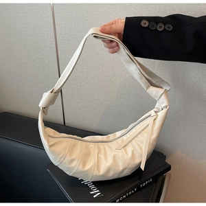 Detailed view of the cream pleated crescent bag with knot shoulder strap and leather zipper