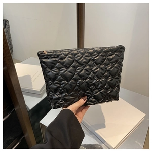 Detail of black heart quilted handbag with metallic zipper and glossy soft texture