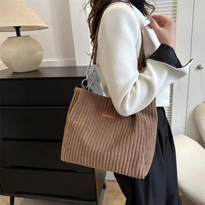Brown corduroy tote bag with chain strap and leather patch shown on person