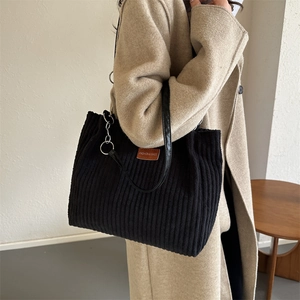 Minimalist black corduroy tote bag with leather strap and fashion label detail