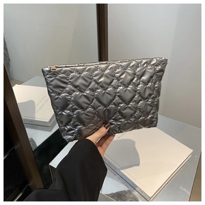 Silver quilted heart texture detail on hand-held crossbody bag with gold metal zipper