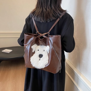 Brown leather tote bag featuring a cute plush dog patch and stylish side zippers for women