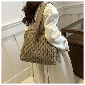 Quilted tote bag showing large capacity and side drawstring details on model