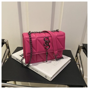 Détail du sac bandoulière matelassé rose avec logo S argenté et pompon sur livres