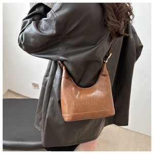 Detail of vintage brown crescent bag showing embossed texture and gold metal buckle