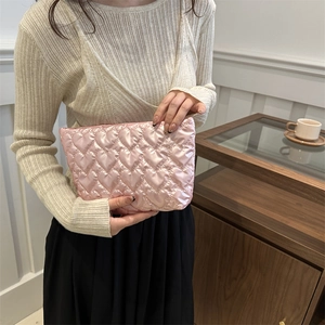 Pink heart quilted small square bag with satin finish held in a cozy cafe setting