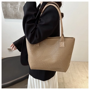 Detail view of khaki woven tote bag showing premium texture and shoulder strap on model