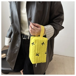 Macro view of bright yellow quilted fabric with black embroidered bows on a fashion handbag