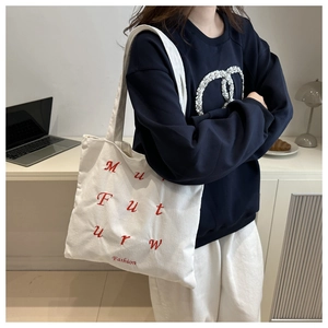 Macro view of white corduroy tote bag with red embroidered fashion lettering and texture