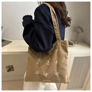 Detailed close-up of khaki corduroy tote bag with white Future Fashion embroidery on side