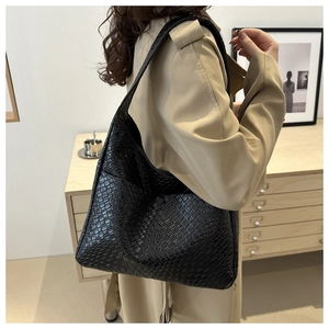 Close-up of a black woven leather tote bag shown on a model for daily commute style