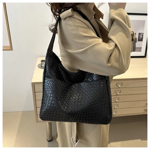 Close-up of the woven texture on a black hobo shoulder bag styled in a modern interior