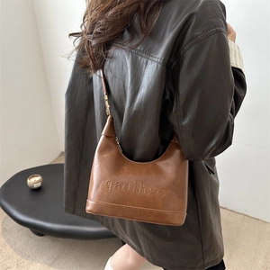 Brown faux leather crescent underarm bag with embossed text and metallic hardware