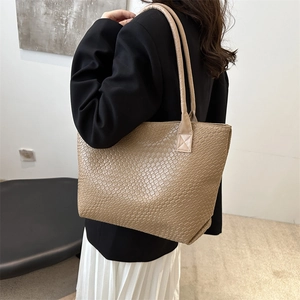 Khaki large capacity woven texture tote bag worn by a model in a modern studio