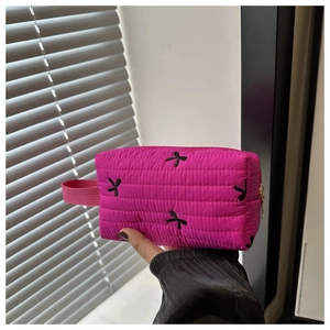 Fuchsia quilted makeup bag featuring black bow embroidery and gold zipper detail