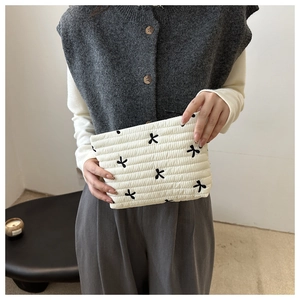 Close-up of white quilted cosmetic bag featuring black bow patterns and soft texture
