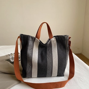 Détail du sac cabas en toile montrant la texture rayée et les poignées orange vif