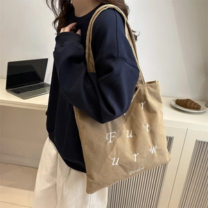 Minimalist khaki corduroy tote bag with embroidery shown in a casual lifestyle setting