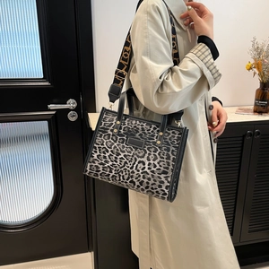 Chic leopard print tote bag with black leather handles and adjustable wide strap