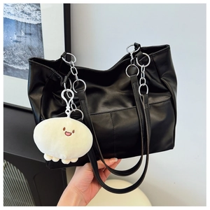 Detail of black tote bag with silver chain strap and cute smiley face plush pendant