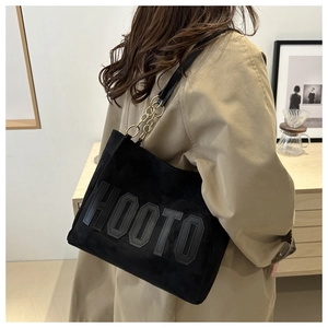 Detail of black tote bag with HOOTO letter patch and metal chain leather strap