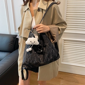 Schicke schwarze Plissee-Tasche mit Wolken-Anhänger, getragen von einem Model im Raum