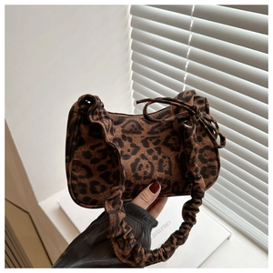 Macro detail of leopard print crescent bag featuring pleated strap and metal zipper