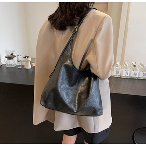 Detail of vintage textured black faux leather tote bag worn as a shoulder bag