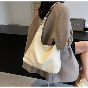 Detail of a large cream tote bag featuring textured leather and wide shoulder strap