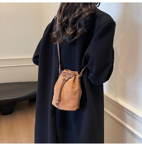 Borsa a secchiello in pelle scamosciata marrone con coulisse su un cappotto nero