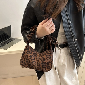 Fashionable leopard print crescent bag with ruffled handle shown in an urban setting