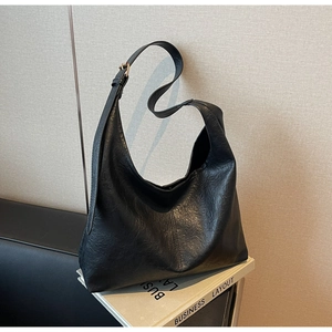 Close-up of black textured leather tote bag with wide strap and vintage metal hardware