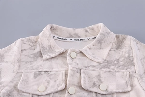 Detail of baby corduroy jacket with lapel collar, snap buttons and marble print