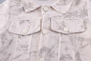 Detail of off-white corduroy jacket featuring marble print and symmetrical chest pockets